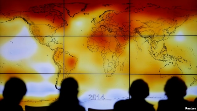 FILE - Participants are seen in silhouette as they look at a screen showing a world map with climate anomalies during the World Climate Change Conference 2015 (COP21) at Le Bourget, near Paris, France, Dec. 8, 2015. 