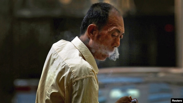 A taxi driver takes a cigarette break in central Beijing, China, May 28, 2012.