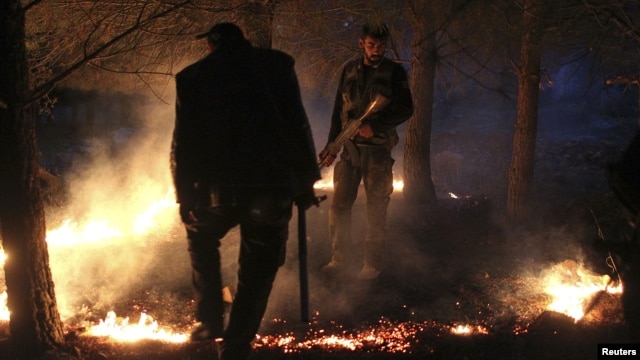 Members of the Free Syrian Army set up a fire to obscure the Kurdish militants' vision, while standing alert during a truce on  top of a hilly mountain in the Kurdish area of al-Qaftal, overlooking the town of Azaz, October 31, 2012. 