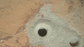 At the center of this image from NASA's Curiosity rover is the hole in a rock called "John Klein" where the rover conducted its first sample drilling on Mars.