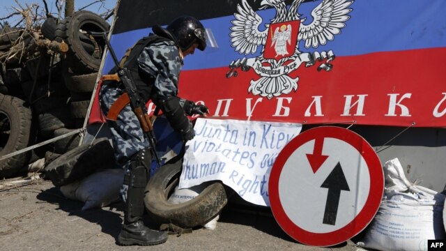 Một người đàn ông vũ trang thân Nga đặt 1 biểu ngữ tại 1 trạm kiểm soát bên ngoài thành phố Slavyansk, miền đông Ukraine, 26/4/2014