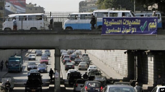 Egyptians drive past a banner calling for a "yes" vote in a referendum on constitutional changes scheduled for Saturday, Cairo, March 17, 2011