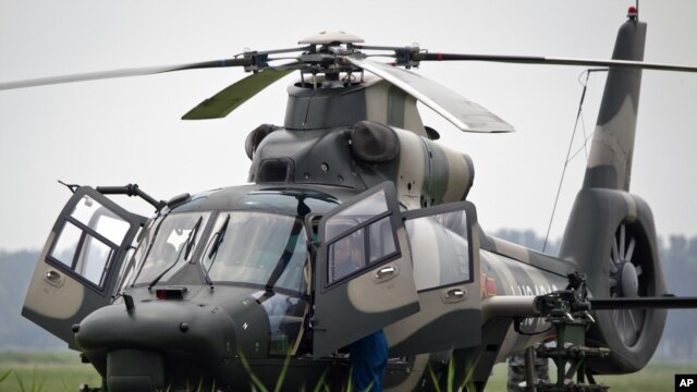 Flight crew of a Z-9WZ attack helicopter, designed and manufactured by China, chat after a flight demonstration for press at a Chinese Liberation Army base, ahead of Army Day on Aug. 1, on the outskirts of Beijing, China Tuesday, July 24, 2012.