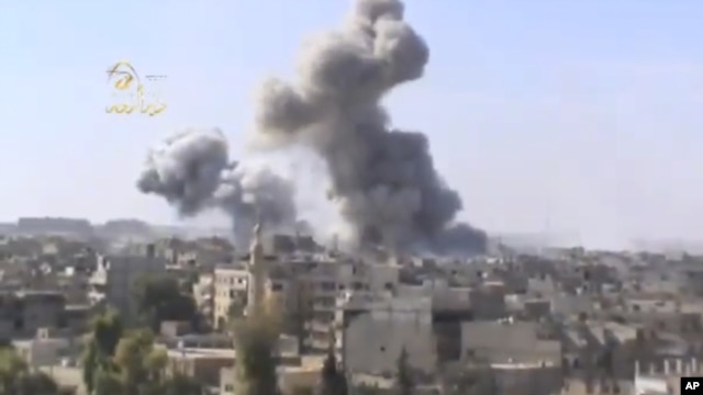 This image taken from video obtained from the Ugarit news network, which has been authenticated based on its contents and other AP reporting, shows smoke rising from the city following heavy bombing from military warplanes, in Deir el-Zour's Jbeileh neigh