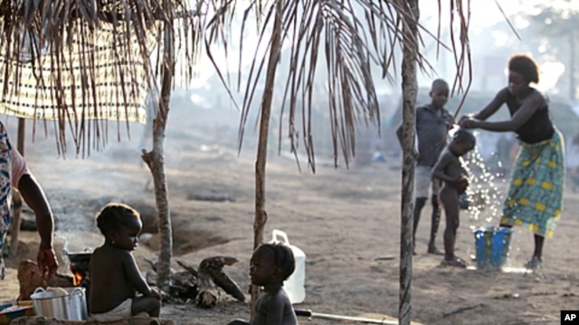 Children sit outside their family's tent as a neighbor bathes her son in a camp housing more than 2,600 Ivorian refugees, with more arriving daily, in Solo Town, near Zwedrou, Liberia, May 25, 2011.