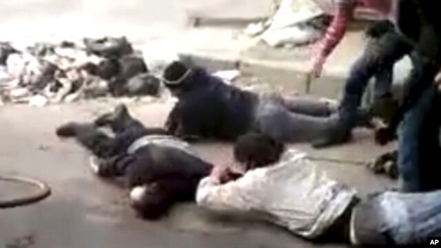 Men retrieve a body, in a rubbish-strewn street in Homs, Syria  December 15, 2011.