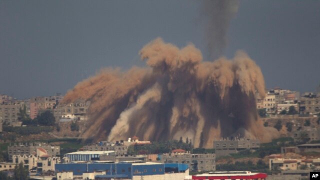 Asap dan puing-puing bangunan menghambur ke atas menyusul serangan Israel di Jalur Gaza (9/7). (AP/Ariel Schalit)