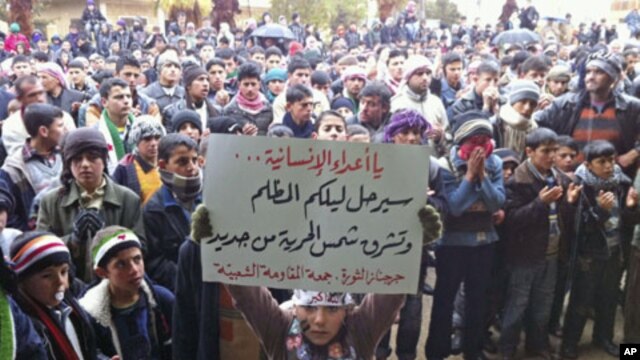 Demonstrators take part in a protest against Syria's President Bashar al-Assad - carrying a sign that reads, 'Enemies of humanity your dark night will go and the new dawn of freedom will rise' - in Jerjenaz, near Idlib, February 17, 2012.