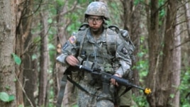 In a May 9, 2012 photo, Capt. Sara Rodriguez of the 101st Airborne Division walks through the woods during the expert field medical badge testing at Fort Campbell, Ky., on May 9, 2012.