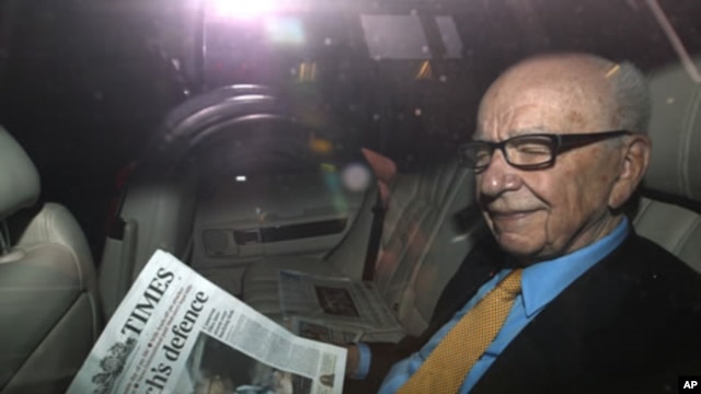 News Corp Chief Executive and Chairman Rupert Murdoch holds a copy of The Times newspaper as he leaves his home in London July 20, 2011