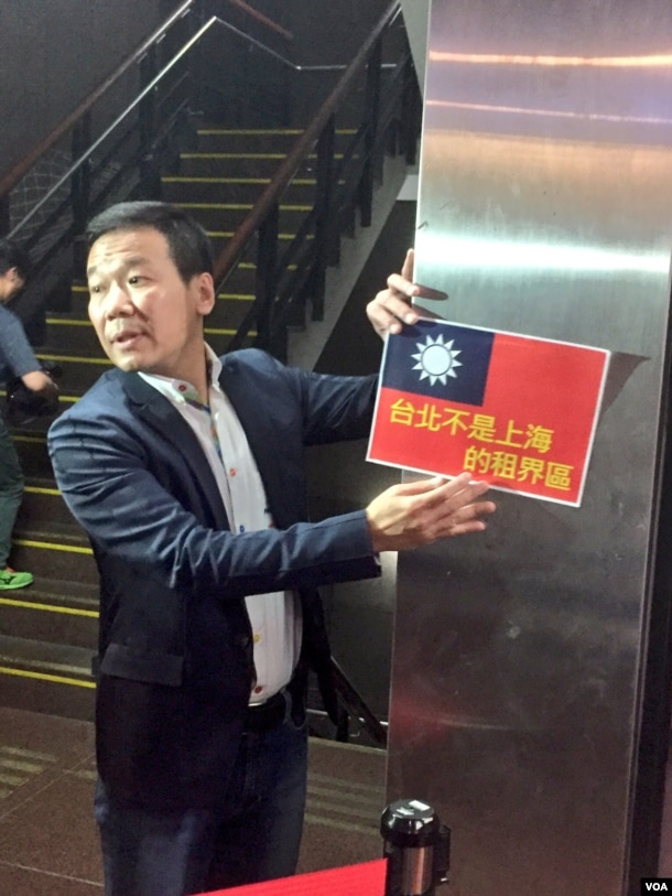 国民党籍台北市议员钟小平向媒体展示抗议标语。他指责柯文哲市长身份款待沙海林是自我矮化。（美国之音林枫拍摄）