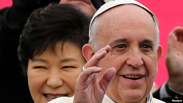 Pope Francis waves upon his arrival at Seoul Air Base, as South Korean President Park Geun-hye (L) smiles, in Seongnam, Aug. 14, 2014.