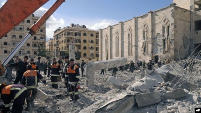 Syrian workers inspect the site of an explosion outside a military security building, one of two sites of bomb blasts in Syria's northern city of Aleppo, February 10, 2012.