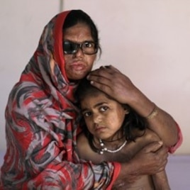 Pakistani acid attack survivor, Azim Mai, 35, holds her daughter Shaziya, 8, while sitting on a bed waiting to have a massage session for their wounds, at the Acid Survivors Foundation (ASF) in Islamabad, Pakistan, December 13, 2011.