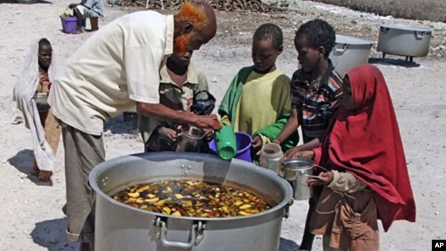 Somali children from southern Somalia, receive cooked food in Mogadishu, Somalia, Monday, Aug 15, 2011