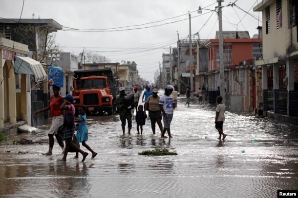 Residents walk on a flooded street after Hurricane Matthew in Les Cayes, Haiti, October 5, 2016.