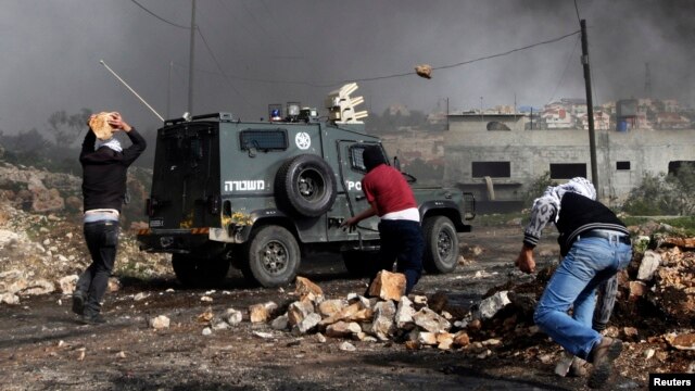 Palestinian protesters throw rocks at an Israeli border police vehicle during clashes at a weekly protest against the nearby Jewish settlement of Kdumim, in the West Bank village of Kfar Kadum, near Nablus, January 25, 2013.