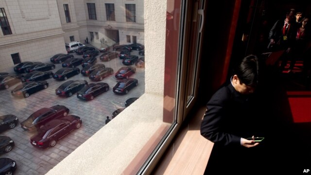 2013年3月5日中国在北京举行第十二届人大开幕式之后，当政府官员的车辆准备离开人民大会堂的时候，一名人大代表查看他的手机。