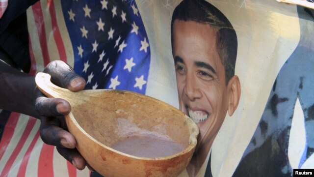 A person holds a bowl of porridge against a poster of U.S. President Barack Obama as Kenyans celebrate his re-election in Nairobi's Kibera slums on November 7, 2012.
