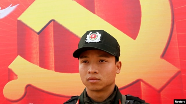 Một cảnh sát đứng canh ở phía trước tấm áp phích  biểu tượng cộng sản bên ngoài Trung tâm Hội nghị Quốc gia.