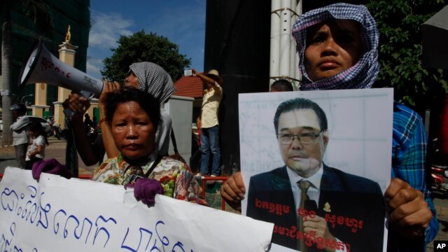 A Cambodian opposition party supporter, right, holds a portrait photo of an opposition senator Hong Sok Hour during a protest in front of the Phnom Penh Municipal Court, in Phnom Penh, Cambodia, Saturday, Aug. 15, 2015. 