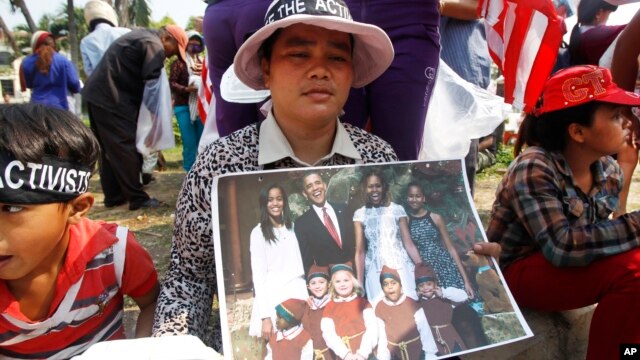 A Cambodian land-grabbing affected villager, center, holds a picture of U.S. President Barack Obama and his family in front of U.S. Embassy in Phnom Penh, Cambodia, Tuesday, March 17, 2015. The group of villagers on Tuesday delivered petition to the embas
