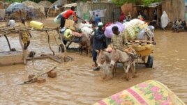 Local residents carry their belongings as they evacuate their homes in Niamey, the capital of Niger, on August 19, 2012.  
