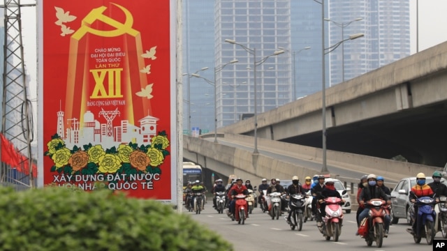 Các phương tiện giao thông đi ngang qua một tấm bảng có nội dung về Đại hội Đảng Cộng sản Việt Nam lần thứ 12, ngày 19 tháng 1 năm 2016.