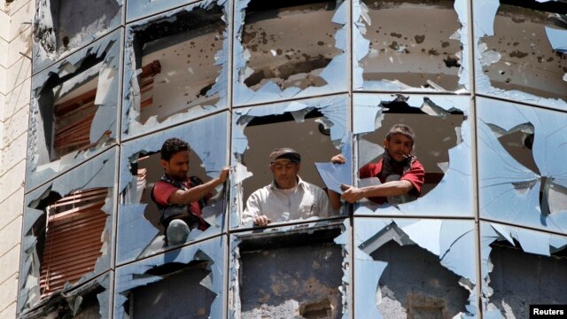 Workers clear broken glass from windows at a group of companies belonging to business tycoon Tawfeek Abdo Al-Raheem, which was damaged by fighting between Shi'ite Houthi rebels and government forces, in Sana'a, Sept. 28, 2014.  