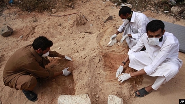 Volunteers dig up corpses in the city of Sirte, October 23, 2011.