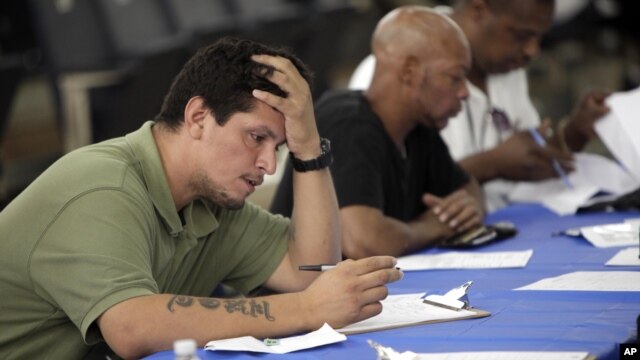 Job seekers fill out applications at a construction job fair in New York, August 21, 2012.