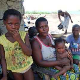 An Ivorian mother sits in the shade with her children at the Koblakan river crossing in Liberia