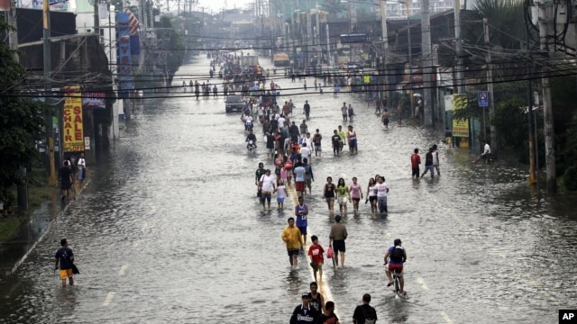 Cư dân đi bộ trên một đường phố ngập nước ở ngoại ô Pasig City, phía đông Manila, Philippines, ngày 9/8/2012