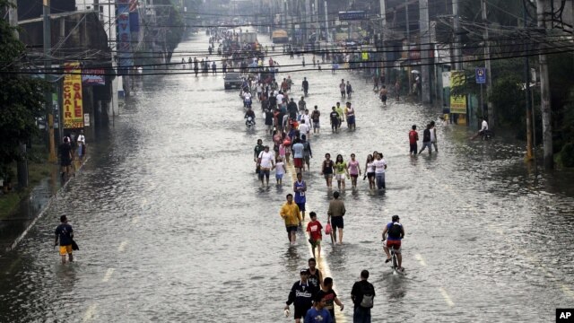 People walk on a flooded street in suburban Pasig City, east of Manila, Philippines, August 9, 2012.