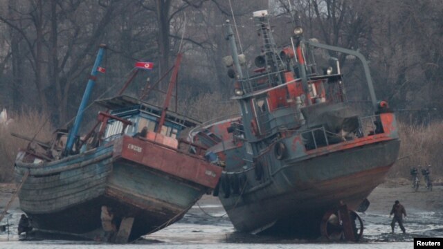 A cargo boat (R) is seen on the bank of the Yalu River in Sinuiju, opposite the Chinese border city of Dandong, March 14, 2016.