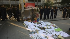 Security guards stand near protest banners and flowers are laid outside the headquarters of Southern Weekly newspaper in Guangzhou, Guangdong province January 7, 2013. 