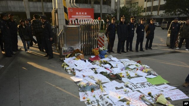 Security guards stand near protest banners and flowers are laid outside the headquarters of Southern Weekly newspaper in Guangzhou, Guangdong province January 7, 2013. 