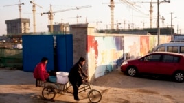 Workers ride a tricycle outside a construction site of a residential real estate project in Beijing, China, January 13, 2013.