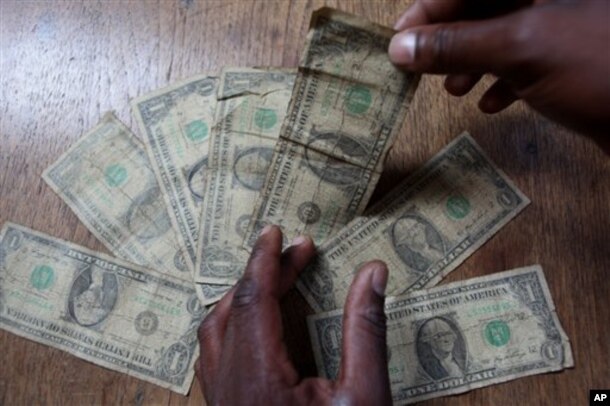 FILE: In this Friday, July 2, 2010 picture an unidentified man shows dirty one dollar notes before washing them in Harare, Zimbabwe. The washing machine cycle takes about 45 minutes.