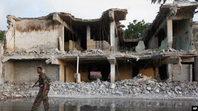 A Somali soldier walks near destroyed buildings, Feb. 27, 2016 after a suicide car bomb on Friday night in Mogadishu, Somalia. 