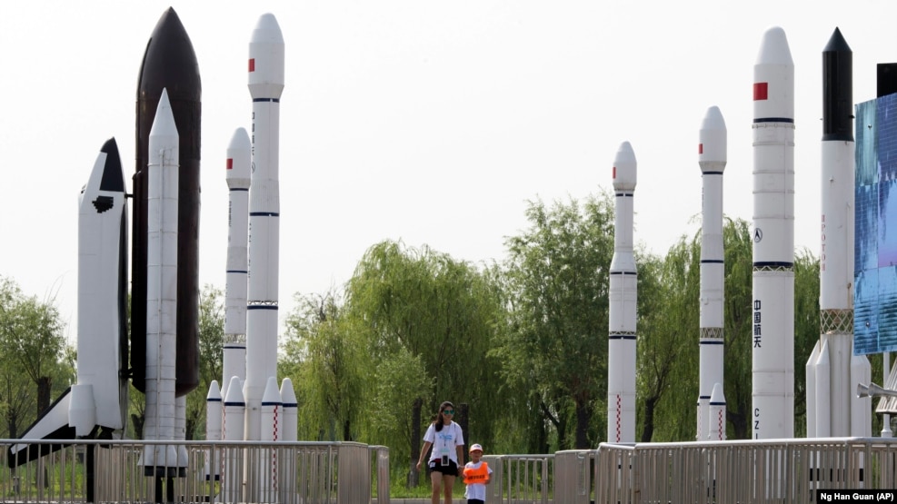 FILE - A woman walks with a child as they visit a park displaying replicas of foreign and domestic space vehicles in Beijing, China, June 26, 2016. China and the United States announced a new round of talks with China about civil space exploration.