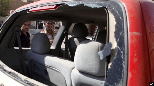Iraqis inspect the scene of a car bomb attack in Baghdad, Sunday, Sept. 30, 2012.