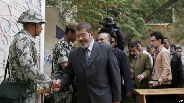 Muslim Brotherhood spokesman Mohammed Morsi shakes hands with a solider on the first day of parliamentary elections in Cairo, Egypt, Monday, Nov. 28, 2011.