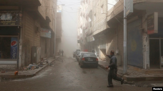 FILE - A man runs while pointing at a site hit by what activists said were airstrikes by forces loyal to Syria's President Bashar al-Assad in Raqqa, eastern Syria, which is controlled by the Islamic State, Nov. 27, 2014. 