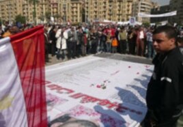 Mourners throw roses and pray over the names of some of those killed in Egypt's revolution, at a makeshift memorial in Tahrir Square, Cairo, February 12, 2011