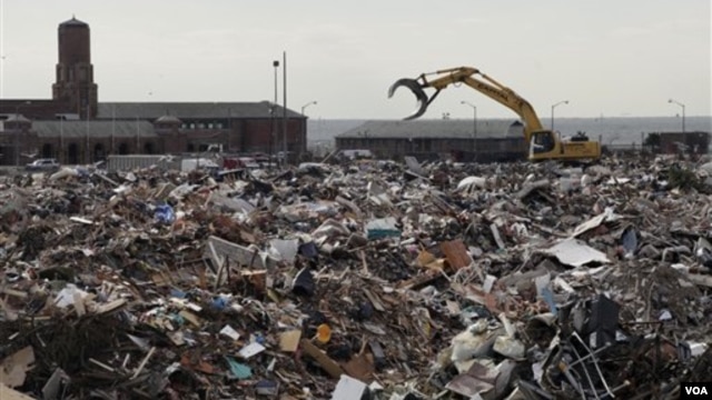 A piece of construction equipment works on the pile of debris, collected during the cleanup from Superstorm Sandy, in the parking lot of Jacob Riis Park in the Rockaway section of the Queens borough of New York, November 14, 2012.