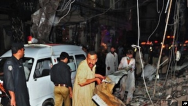 Pakistani people remove debris as they search for blast victims at the site of twin bomb blasts in Peshawar on June 11, 2011.