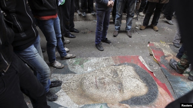 Demonstranti gaze po slici predsednika Bašara al-Asada, tokom protesta protiv njegovg režima u Alepu, 4. januara 2013.