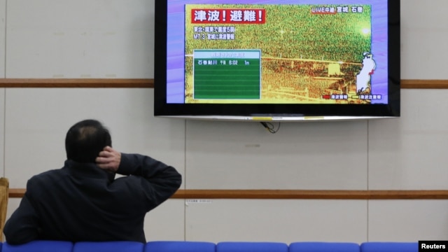 A man scratches his head as he watches television showing live camera footage from Ishinomaki, Miyagi prefecture and an alert sign that reads,"Tsunami! Evacuate!" at Nagano train station, central Japan December 7, 2012