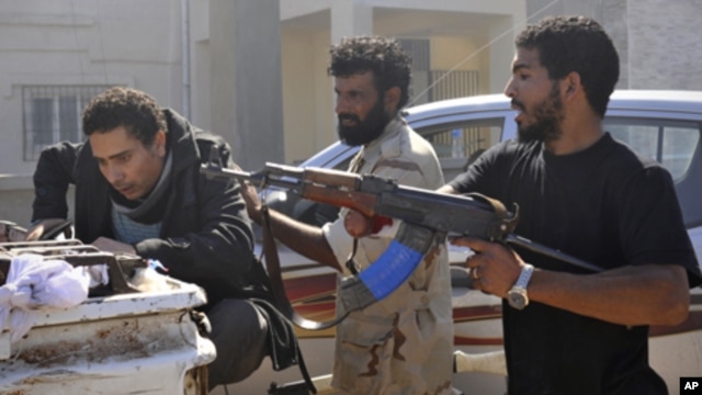 Libyan revolutionary fighters detain a suspected loyalist, left, in downtown Sirte, Libya, Wednesday, Oct. 12, 2011.